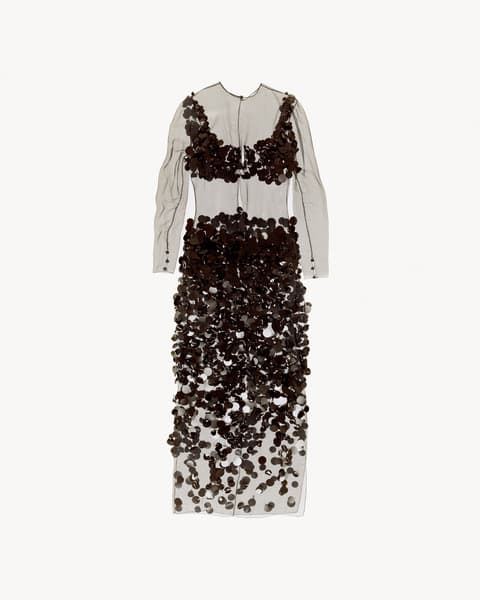 Long sheer dress with long sleeves, decorated with clusters of dark circular appliqués covering the bust, hips, and extending down the skirt, displayed flat against a white background.