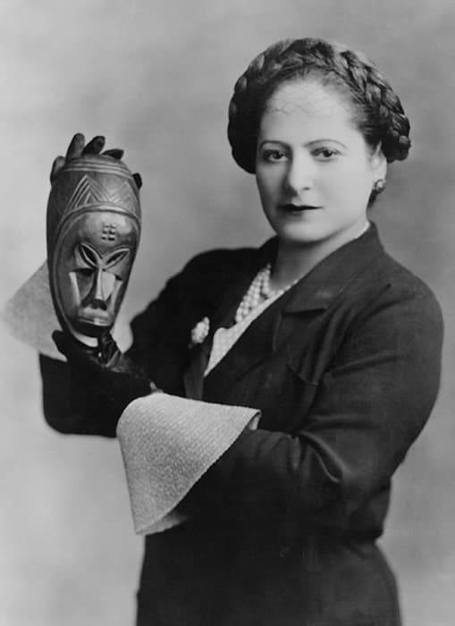 Helena Rubinstein holding one of her masks from the Ivory Coast, 1934. 
Photograph by George Maillard Kesslere. Helena Rubinstein Foundation Archives, Fashion Institute of Technology, SUNY, Gladys Marcus Library, Special Collections