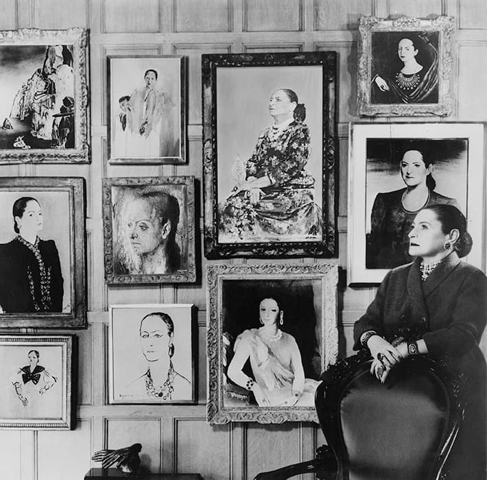 Helena Rubinstein in front of a montage of some of the many portraits she commissioned throughout her life, 1958. Helena Rubinstein Foundation Archives, Fashion Institute of Technology, SUNY, Gladys Marcus Library, Special Collections