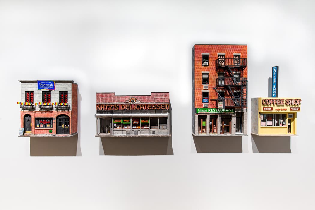 Q PANORAMA

Nicholas Buffon, The Stonewall Inn, 2017; Katz’s Delicatessen, 2017; Odessa, 2016; Lower East Side Coffee Shop, 2016
Foam, glue, paper, paint
Courtesy of the artist and Callicoon Fine Arts, New York

The original purpose of Paris’s covered shopping passages was to preserve shoppers from the dirt and disorder of the streets: from hanging laundry, cooking smells, stray animals, foul weather, and the general cacophony of urban life. They were idealized microcosms of the city. The nineteenth-century panorama was another kind of artificial, miniaturized environment, a precursor of the cinema. A typical panorama was a cylindrical room whose interior walls were lined with theatrically lit paintings and sculptures depicting a scene: a historic battle, an exotic jungle, the depths of the sea. Walter Benjamin saw the panorama as a self-contained world within a world.

Nicholas Buffon’s dioramas pay homage to contemporary American cities by replicating with minute accuracy the most mundane aspects of the urban environment—parking meters and fire hydrants, air-conditioning units and delivery trucks, drooping houseplants and crushed milk cartons. They are panoramas of the unspectacular: instead of offering escape to a faraway place or time, they radiate tenderness for the careworn, disheveled places in which we live.