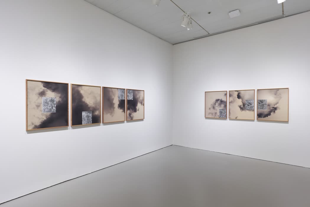 Gallery view featuring two groups of framed abstract works on paper, each combining sepia-toned cloudy forms with small detailed patterned squares, mounted on white walls.